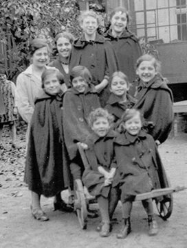 Schwarz-weiß-Aufnahme von mehreren Kindern auf einem alten Holzwagen.