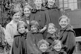 Schwarz-weiß Foto von Kindern auf einer Schubkarre.