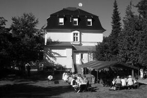 Schwarz-weiß Foto Bertha Pappenheim-Haus, Gartenansicht mit feiernden Menschen