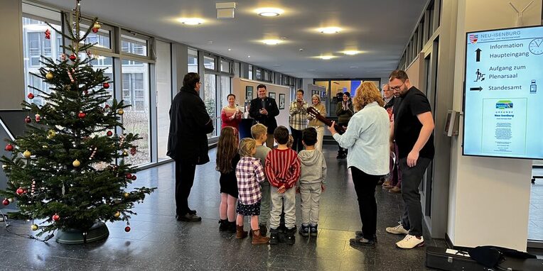 Kinder von hinten im Foyer des Rathauses mit einem Weihnachtsbaum